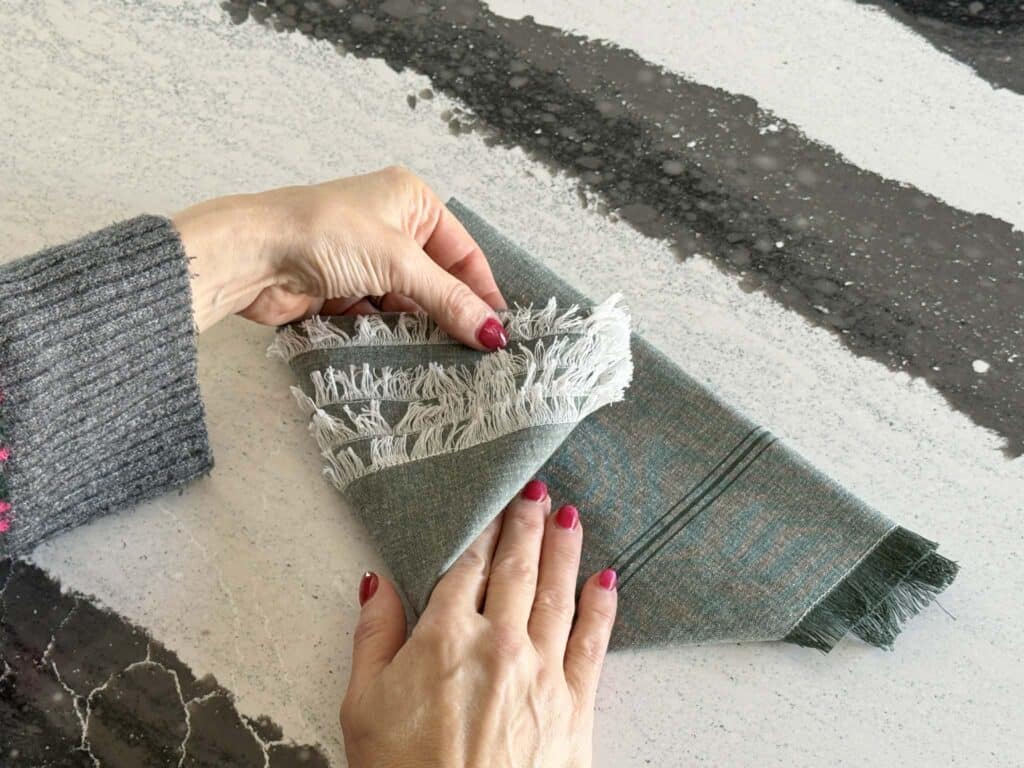 Folding the side of a folded cloth napkin.