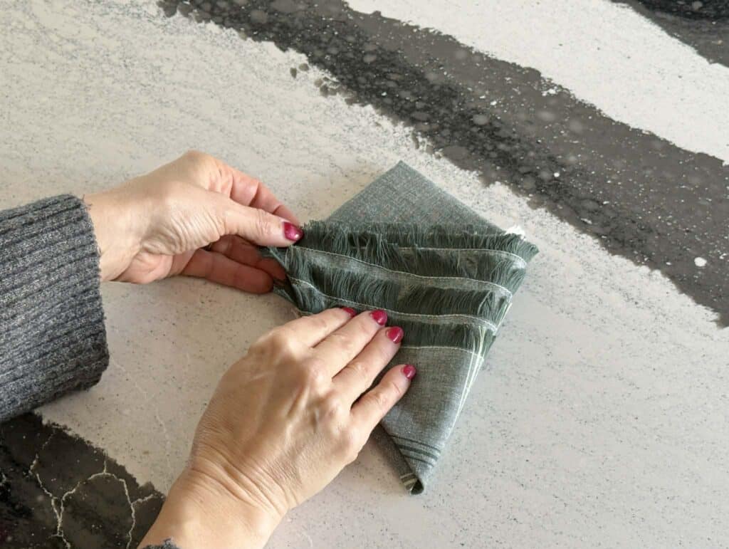 Folding the right side of a folded Christmas tree napkin fold.