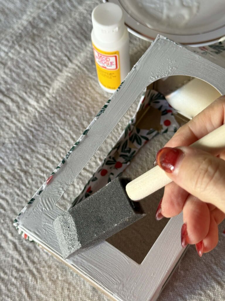 Brushing decoupage glue onto a metal lantern.