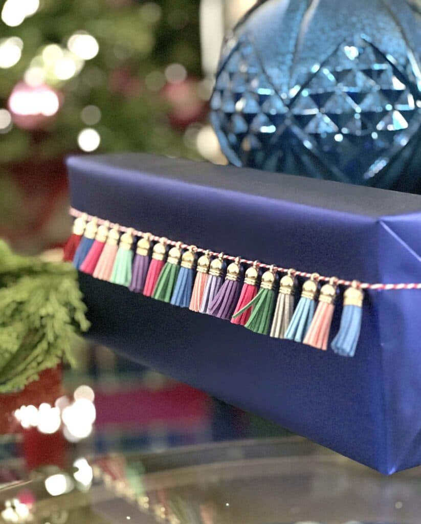 Colorful mini tassels tied to the front a Christmas gift as a wrapping idea.