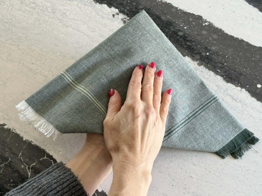 Holding cloth napkin folds in place with hands.
