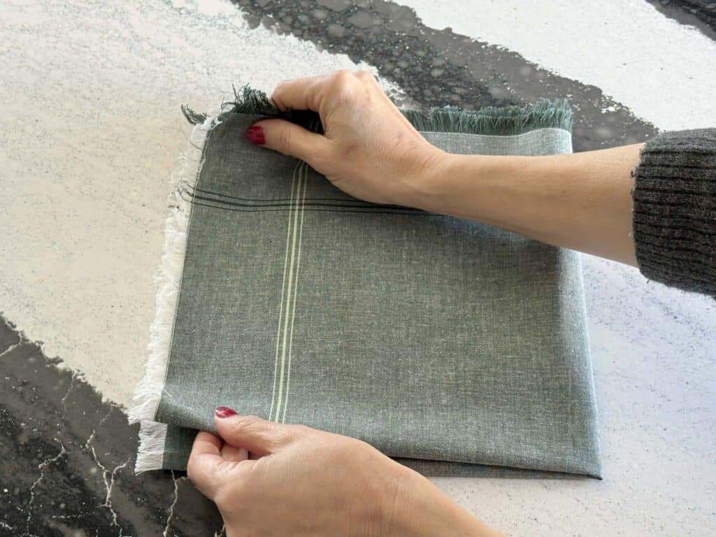 Folding a cloth napkin into fourths.