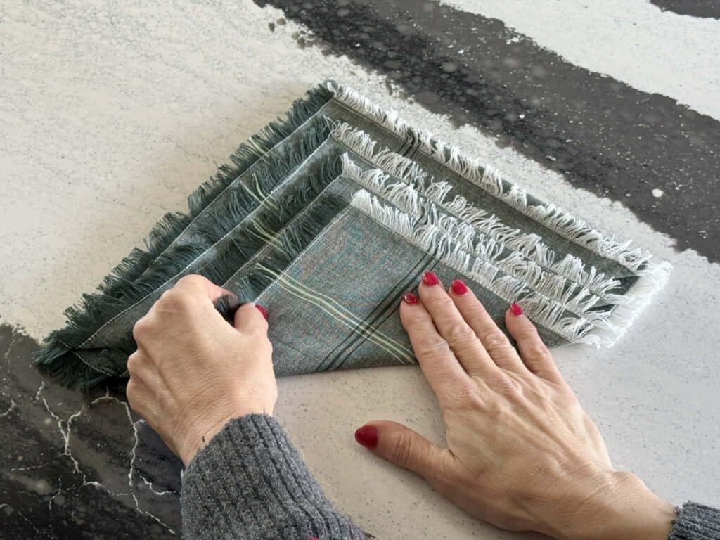 Folding the final layer of a cloth napkin to. create a Christmas tree.
