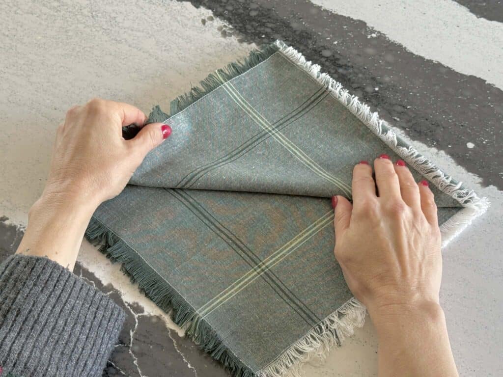Folding open layers of a Christmas cloth napkin upward.