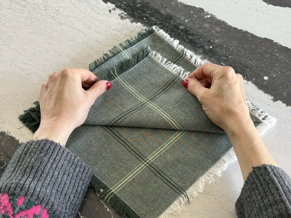 Folding a second layer of a Christmas tree napkin fold.