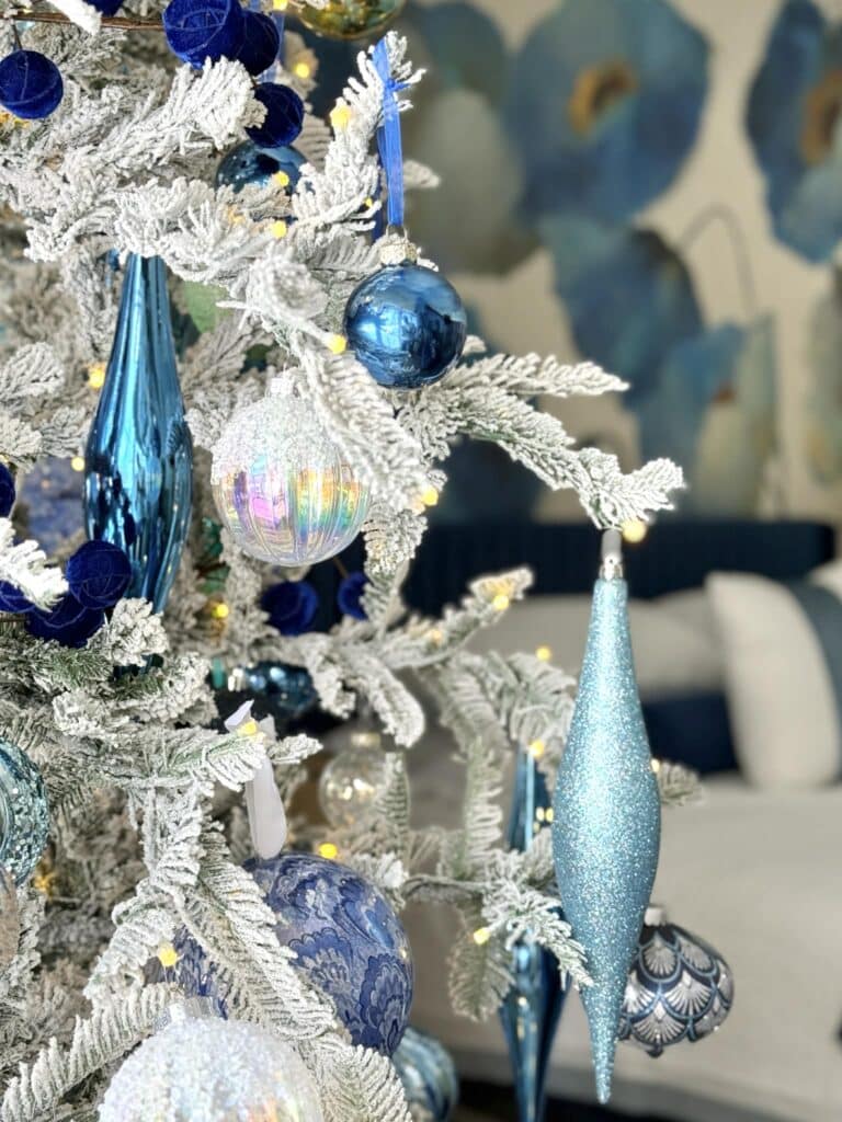 A flocked Christmas tree decorated with blue ornaments.