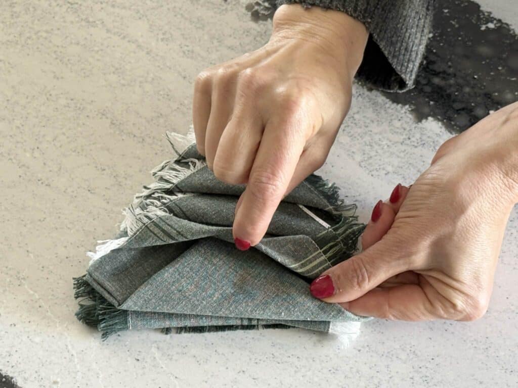 Tucking final cloth tip into napkin bundle.