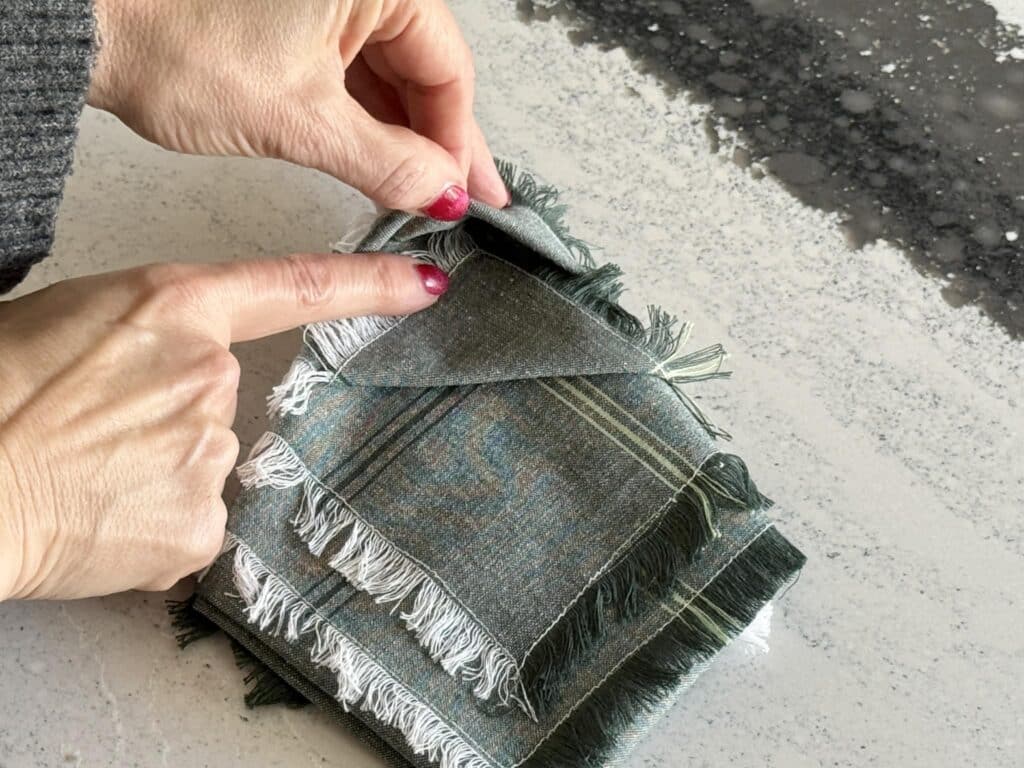 Tucking a fabric tip into a napkin fold to create a Christmas tree.