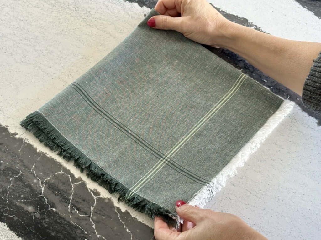 Adjusting placement of a cloth napkin for a Christmas fold project.