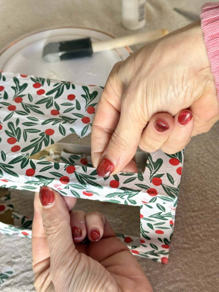 Folding tissue paper around metal Christmas lantern.