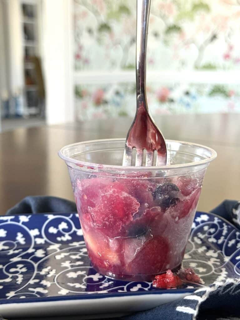 A fork sticking upright in a frozen fruit cup.