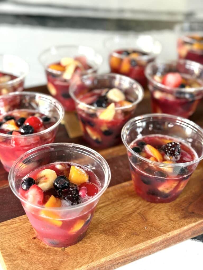 Sugared fruit mixture spooned into plastic cups before going into the freezer.