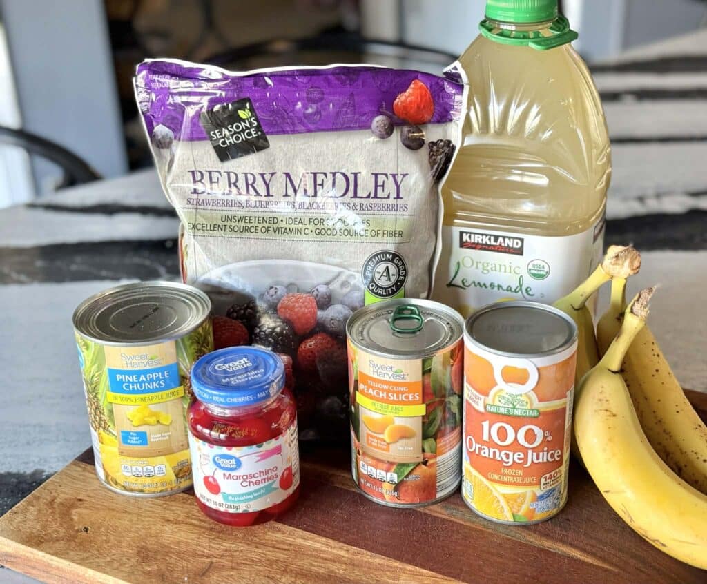 Frozen berries, lemonade, orange juice, pineapple chunks, and a jar of Maraschino cherries.