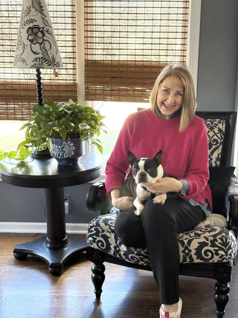 Woman sitting in a chair holding a Boston terrier dog.