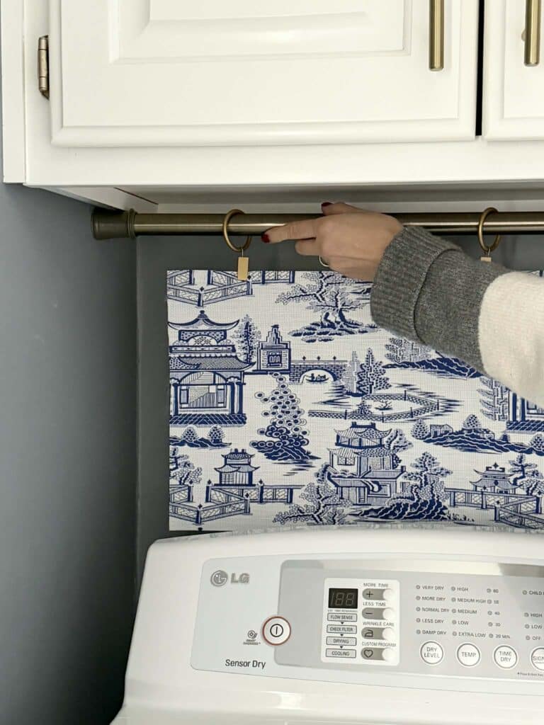 Placing tension rod between walls by washer and dryer in the laundry room.
