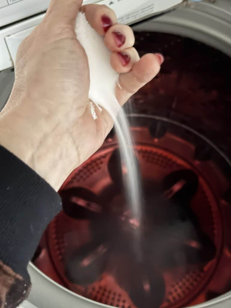 Pouring salt into a dye bath in a washing machine.