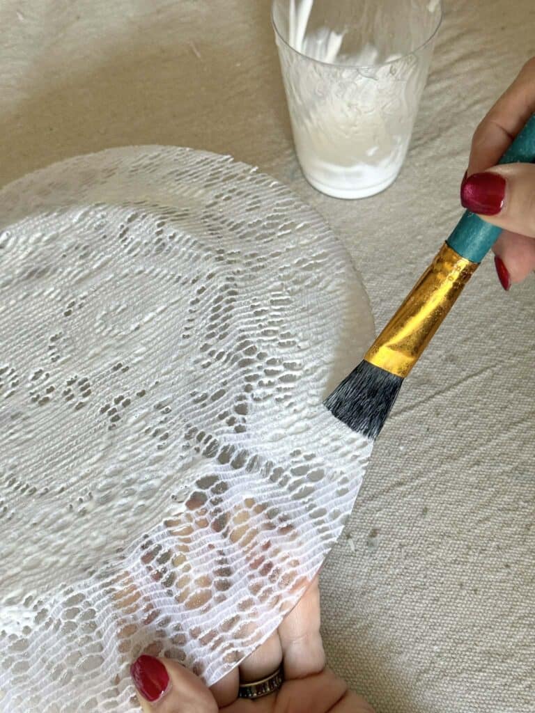 Brushing and additional coat of decoupage glue onto a glass plate.