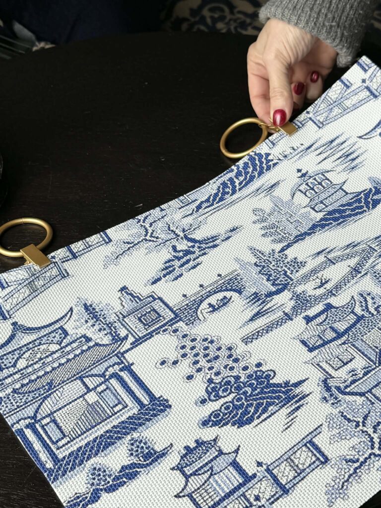 Clipping a curtain ring onto a placemat to hide washer hookup in laundry room.