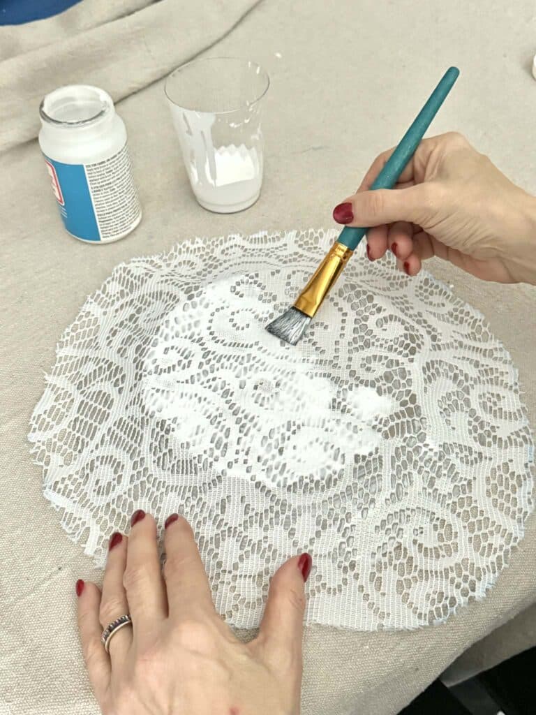 Pouncing decoupage glue onto a lace covered plate.
