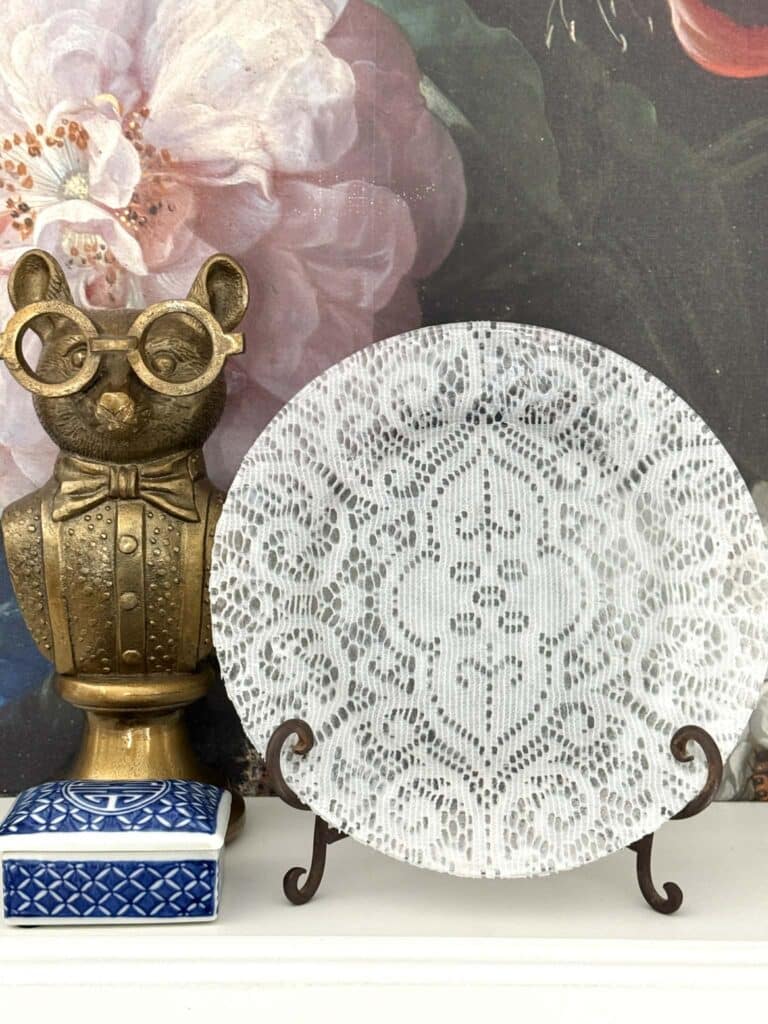 A lace covered decoupage plate on an easel.