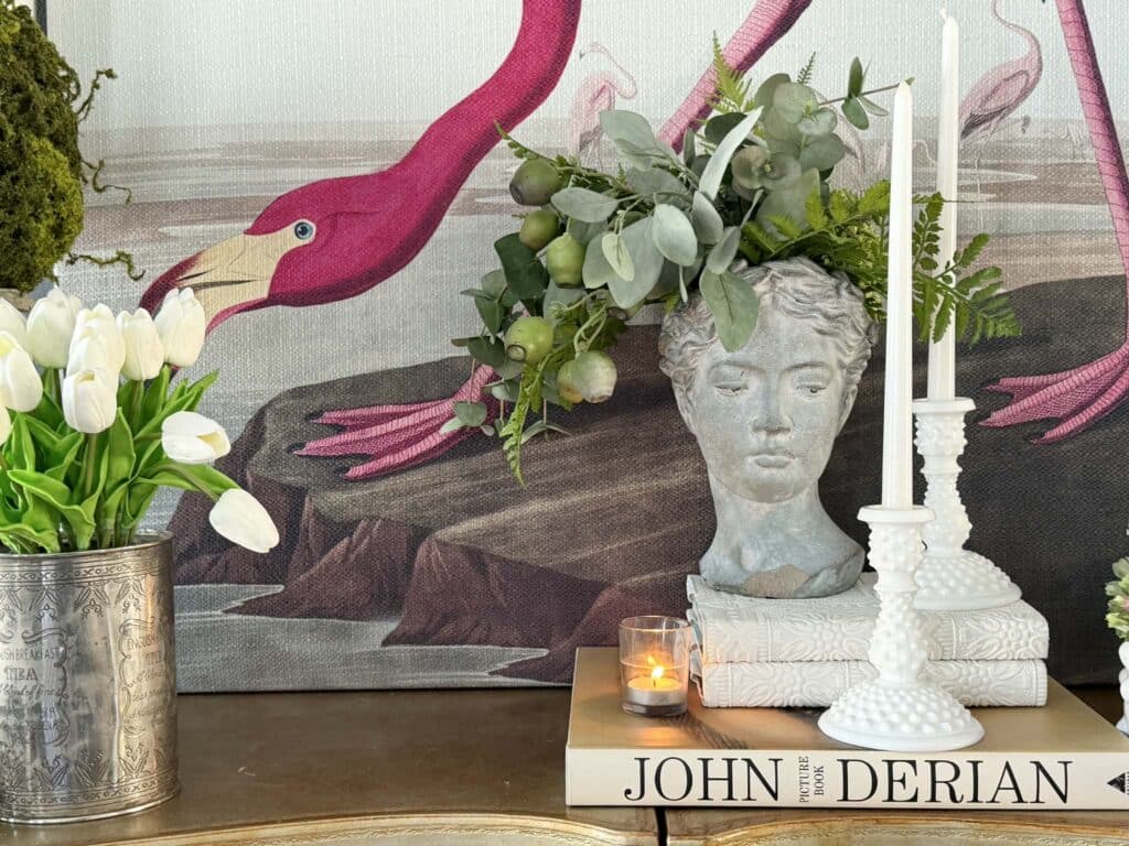 A female bust and candlesticks on top of a stack of books for a design vignette.