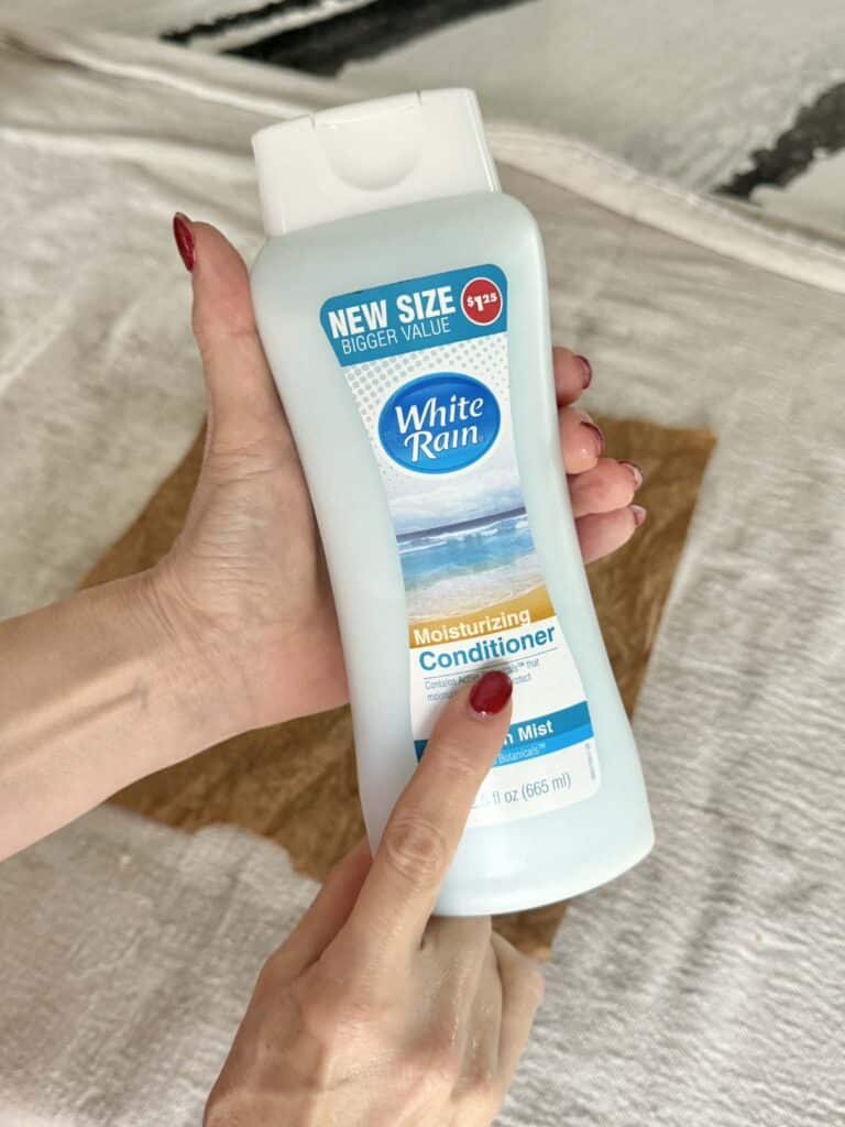 Hand holding a bottle of hair conditioner for paper bag art project.