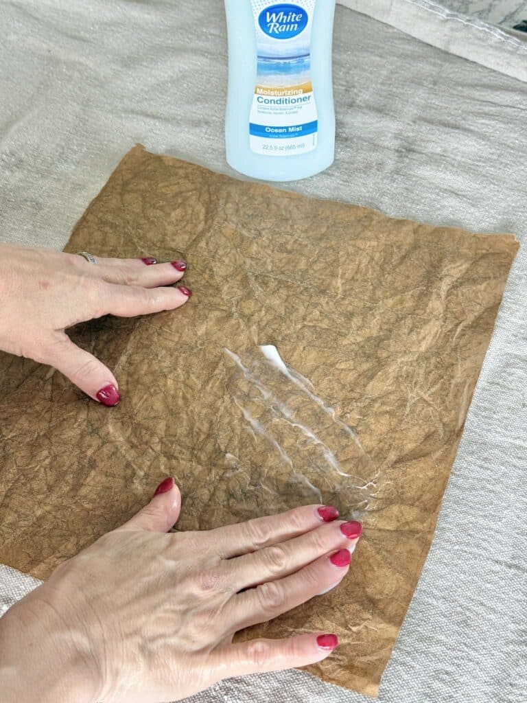 Rubbing hair conditioner onto paper from a grocery bag for an art project.