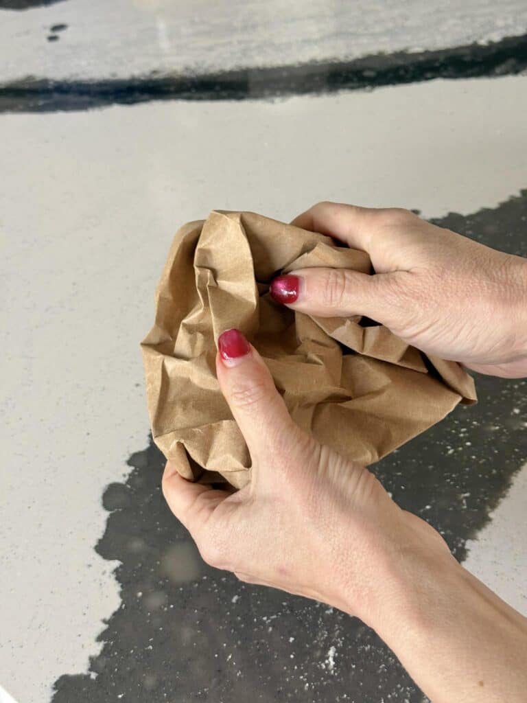 Scrunching a piece of paper from a grocery sack for paper bag art.