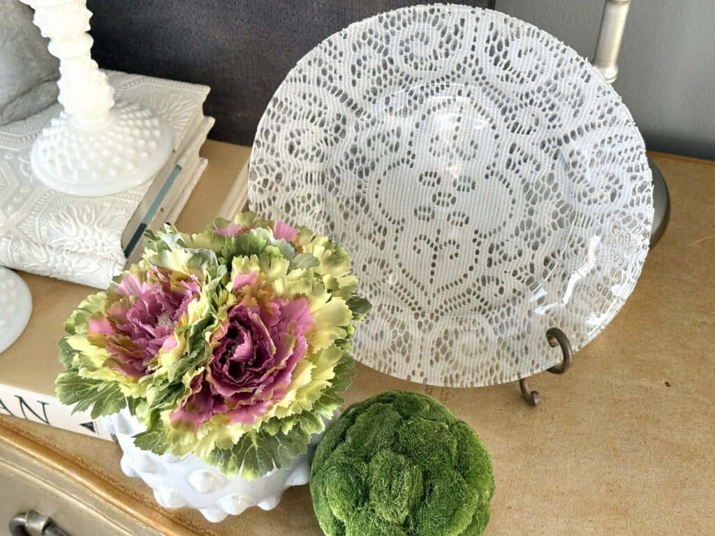 A lace decoupage plate sitting on a console table.