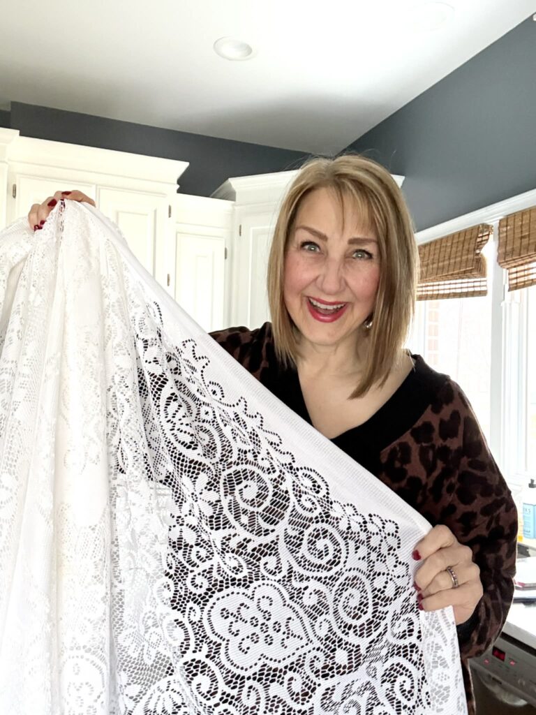 Woman holding a lace tablecloth.
