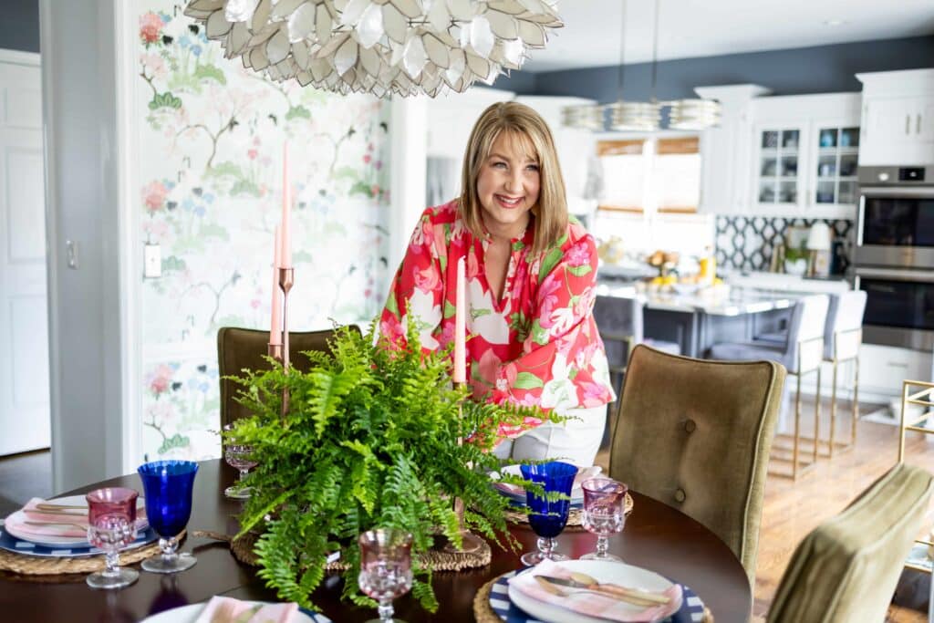 A woman setting a grandmillennial style dining table.