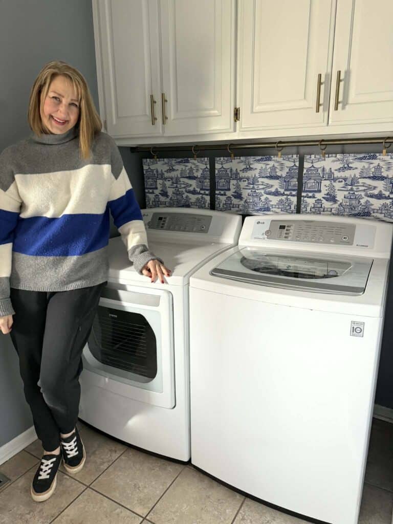 Woman standing beside a washer and dryer.