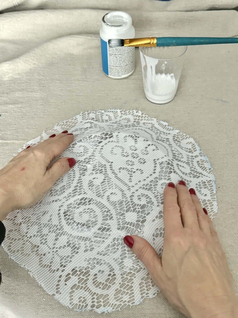 Pressing fabric lace onto the back of a decoupage glued glass plate.