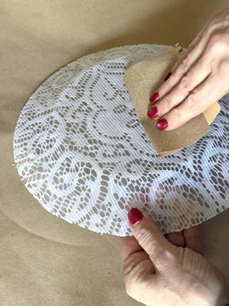 Sanding the back of a decoupage plate.