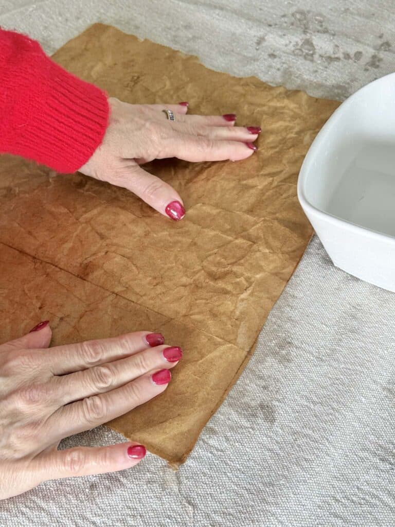 Sprinkling water onto a piece of paper from a grocery bag for an artwork project.