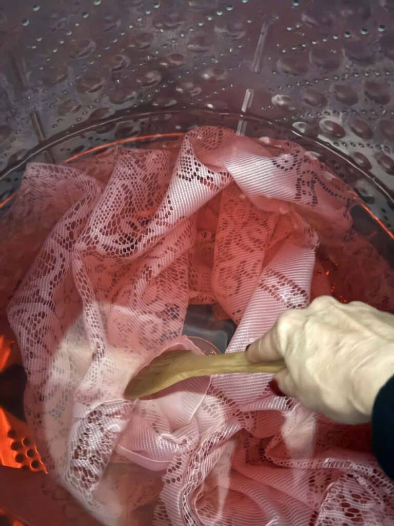 Stirring lace fabric in a dye bath in a washing machine.