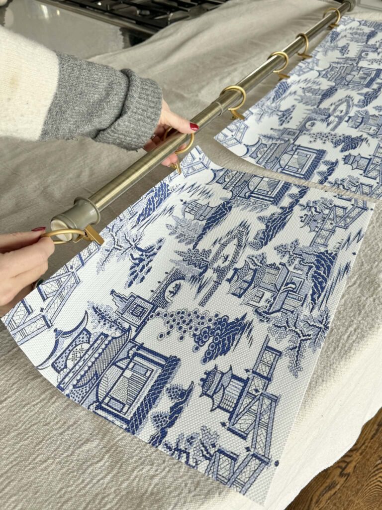 Sliding placemats onto tension rod to cover washer hookup in laundry room.