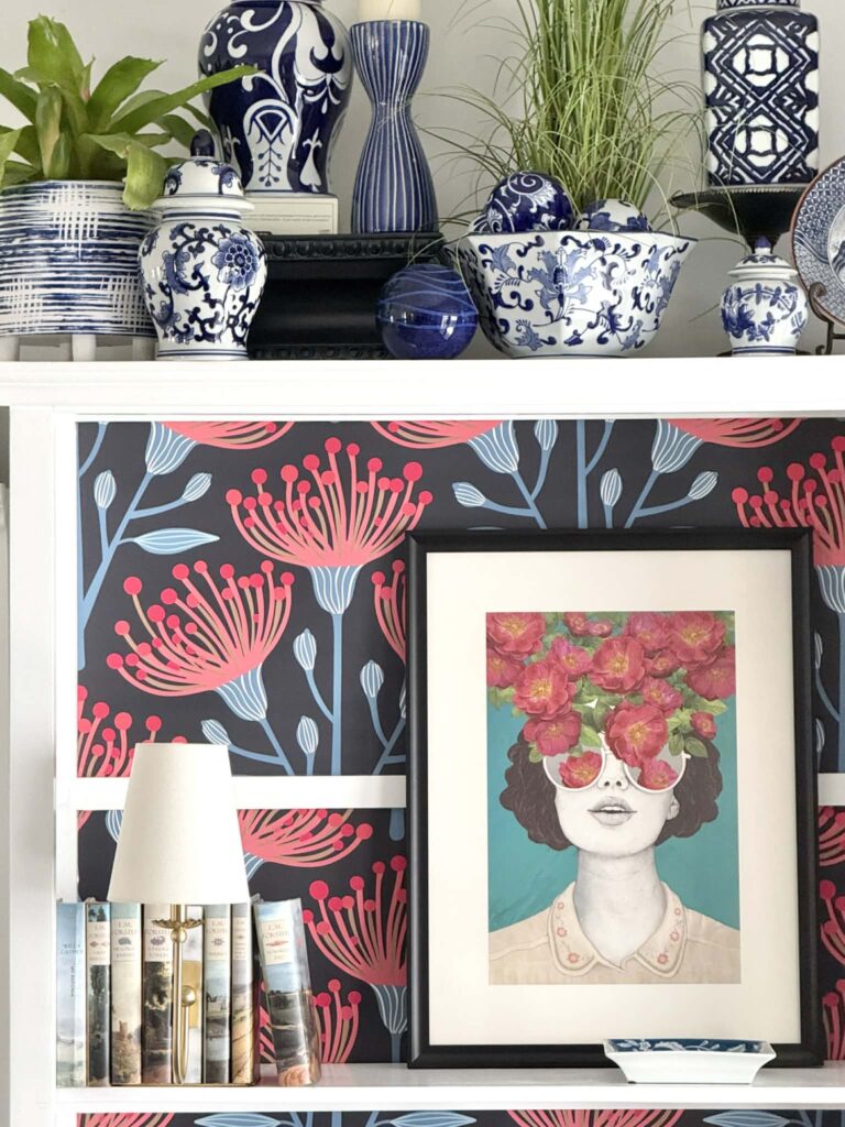Artwork of a woman with glasses sitting on a bookshelf.
