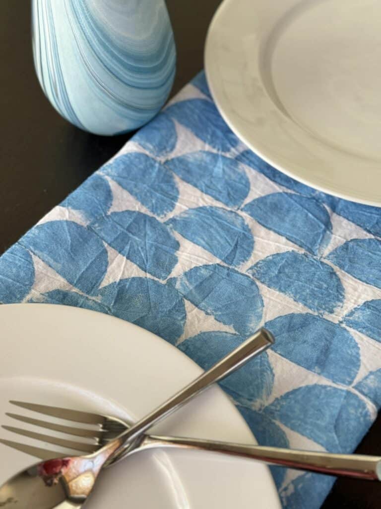 A tea towel used as a table runner after being block printed with a potato.