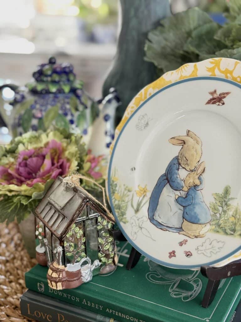 A vintage bunny plate with a glass greenhouse ornament.