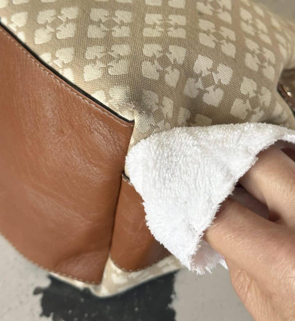 Rubbing a wet white cloth against bottom of canvas bag to check for color fastness.