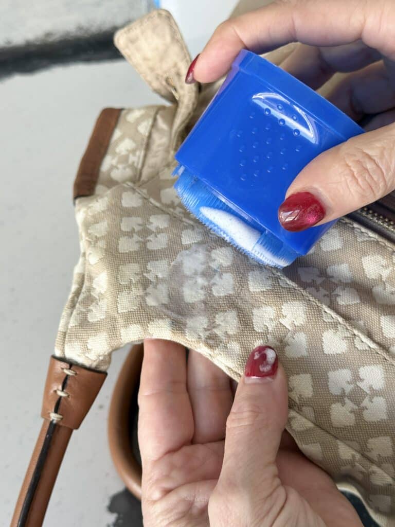 Applying cleaner to canvas bag.