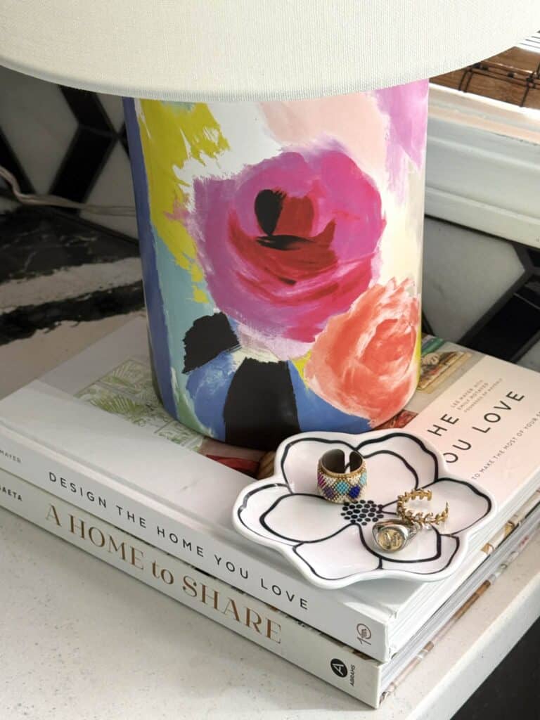 A lamp base with pink and orange flowers on a stack of books.