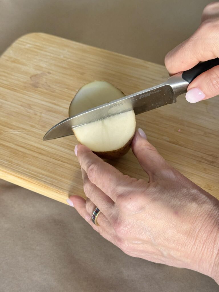 Cutting a potato into a half moon for potato printing.