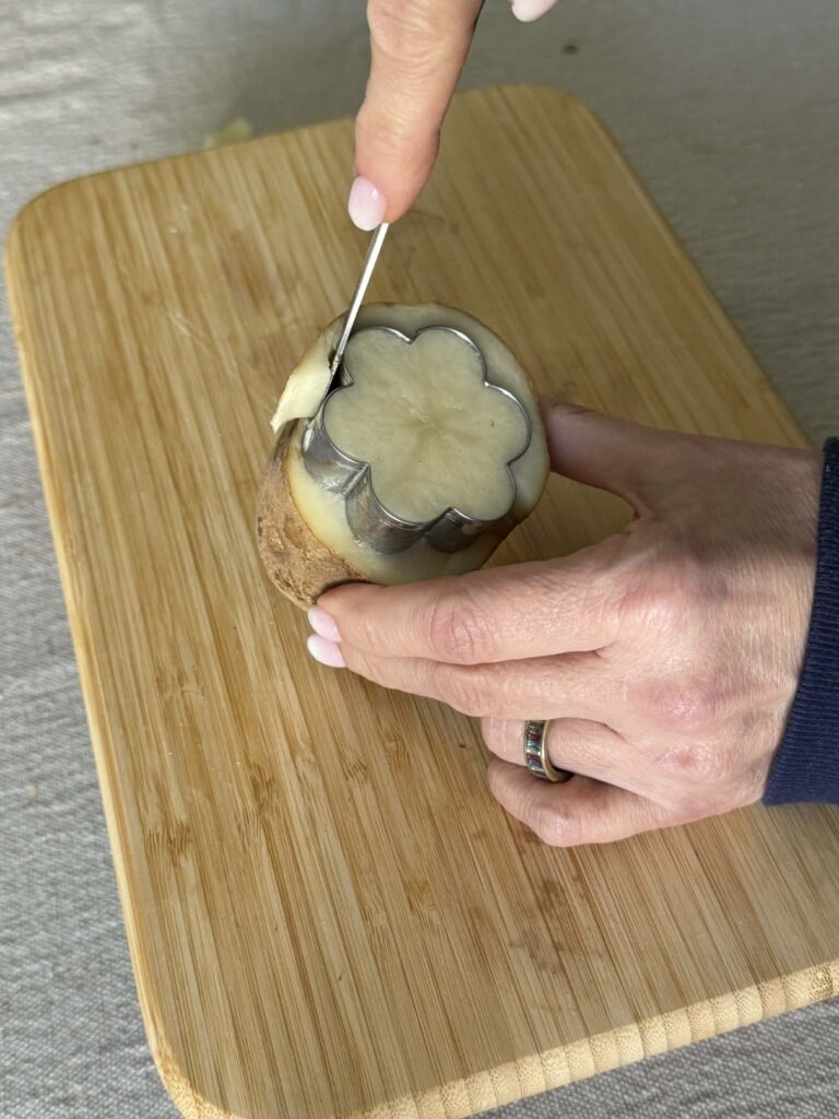 Cutting around a cookie cutter pressed into a potato.