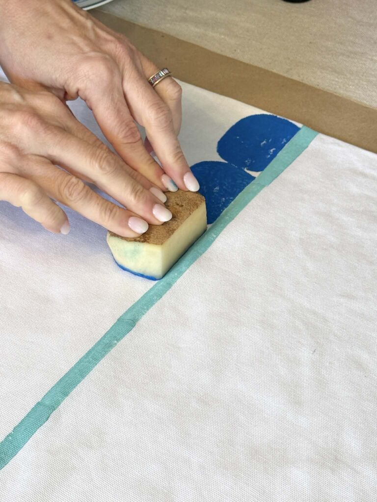 potato printing half moon shapes onto a tea towel in a dark blue color.