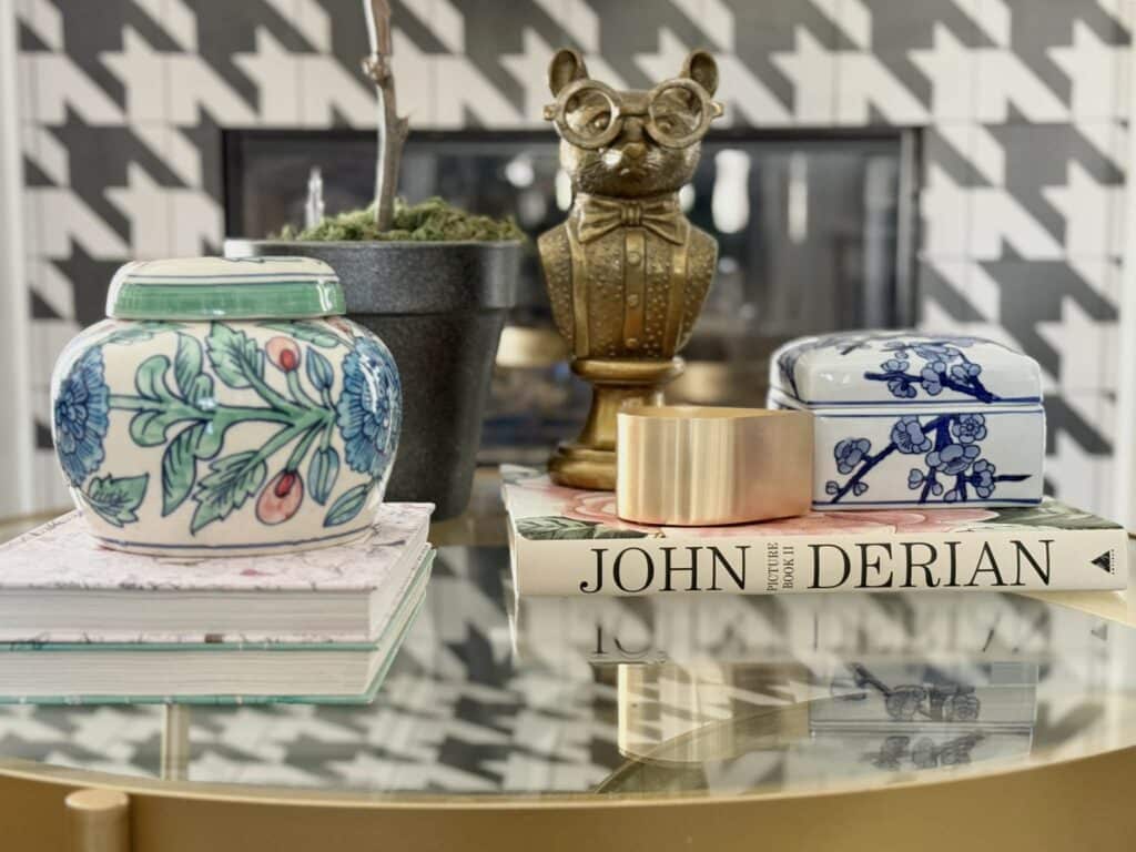 a coffee table with grandmillennial style: John Derian book, colorful vases, and a brass mouse with glasses.