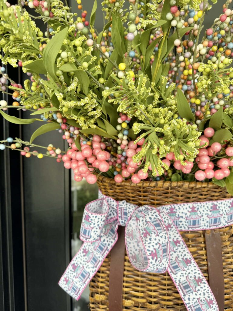 A pink and blue chinoiserie pattern ribbon wrapped around a basket hanging on the front door.