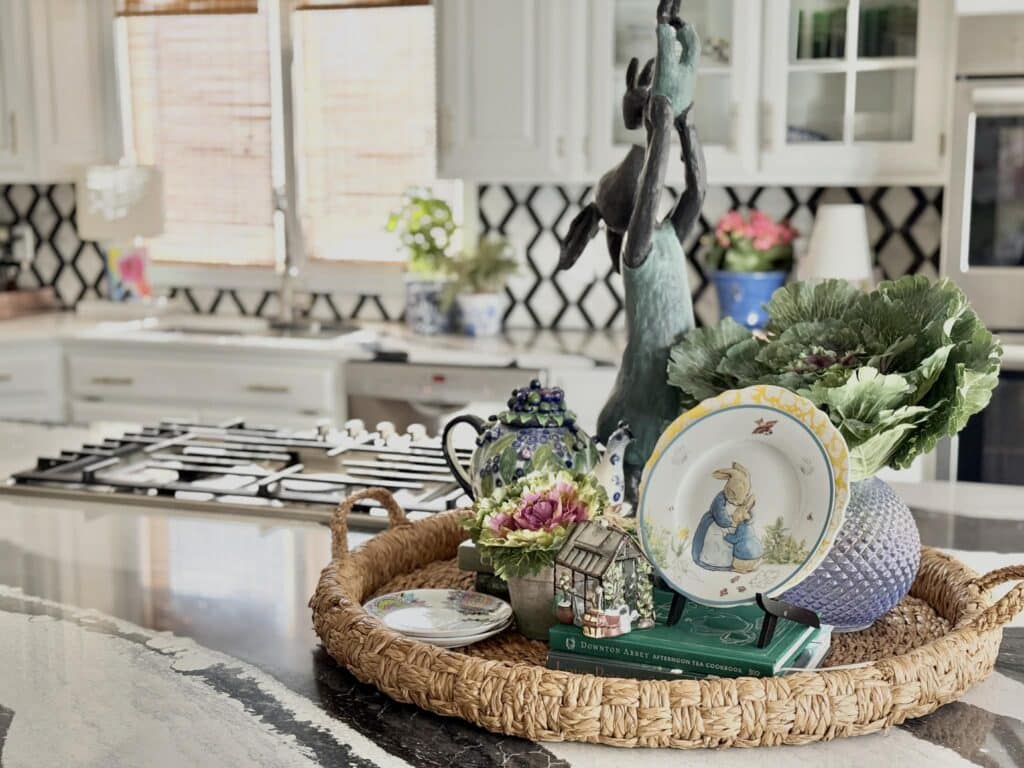 A kitchen island tray styled with vintage plates, a teapot, faux cabbages, and a bunny figurine.