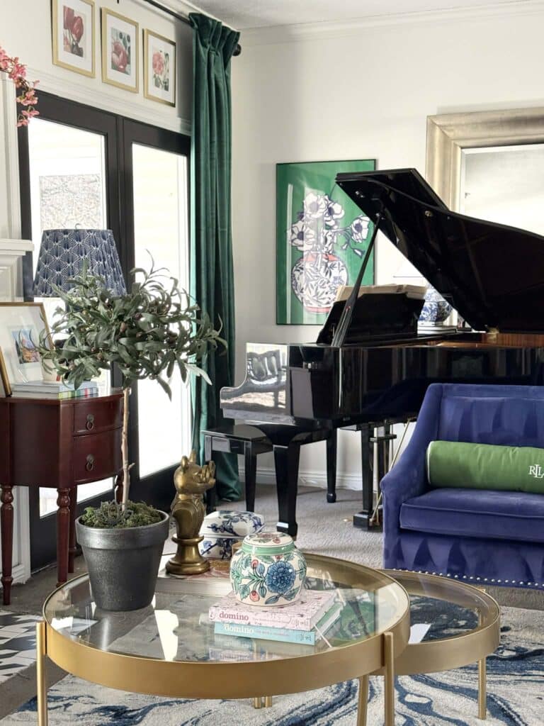 A baby grand piano beside a cobalt glue chair surrounded by grandmillennial style decor.